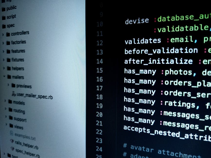 A person using a laptop on a dark, smooth table surface, with their hands resting on the keyboard. The laptop screen displays lines of computer code with syntax highlighting in various colors includin